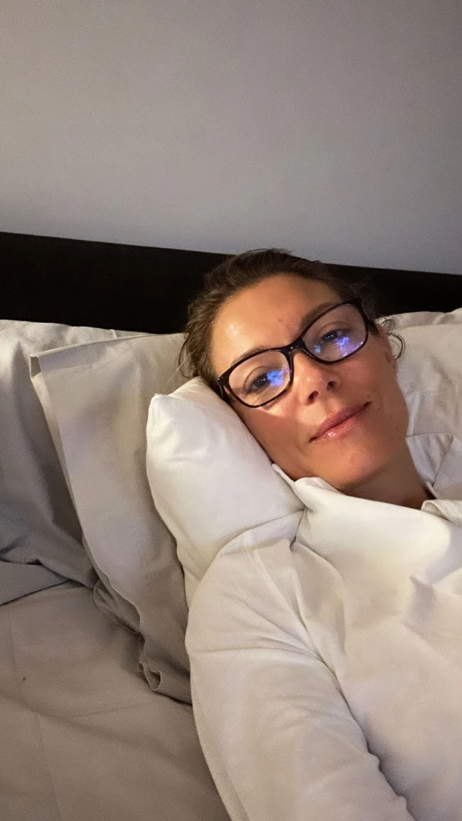 Η Βίκυ Καγιά ποζάρει άβαφη, στο κρεβάτι της, φορώντας γυαλιά μυωπίας και πιτζάμες