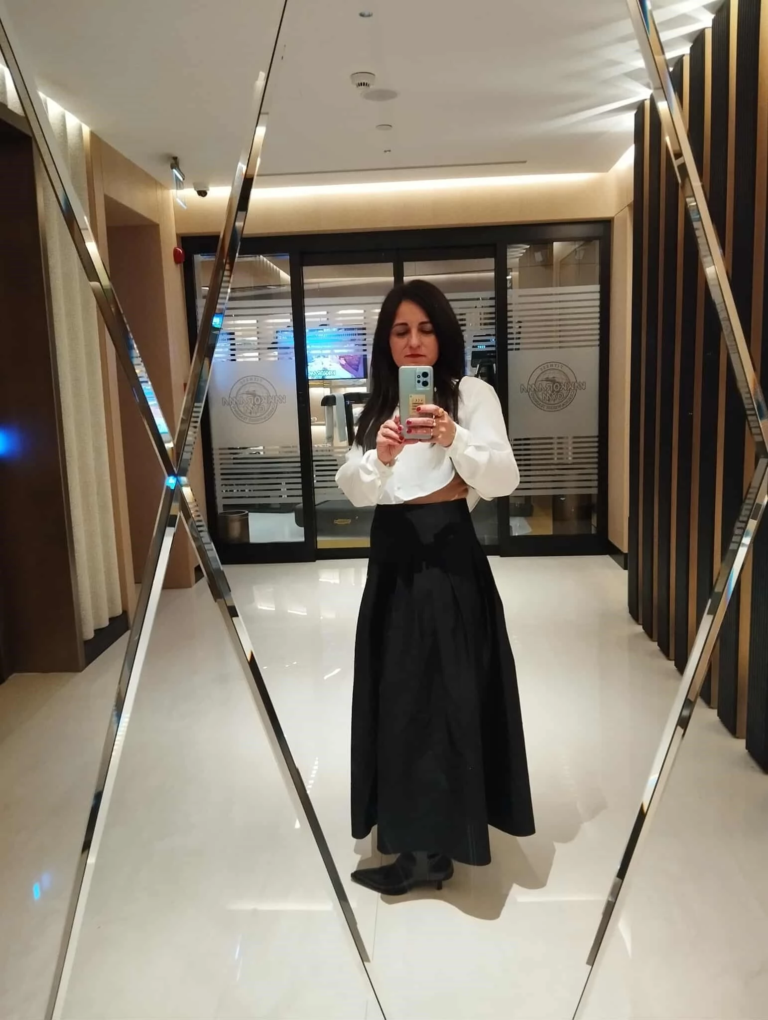 Δήμητρα Βγενοπούλου, fashion editor: Εμφάνιση με πλισέ μαύρη φούστα, σατέν cropped τοπ και μαύρες μπότες.