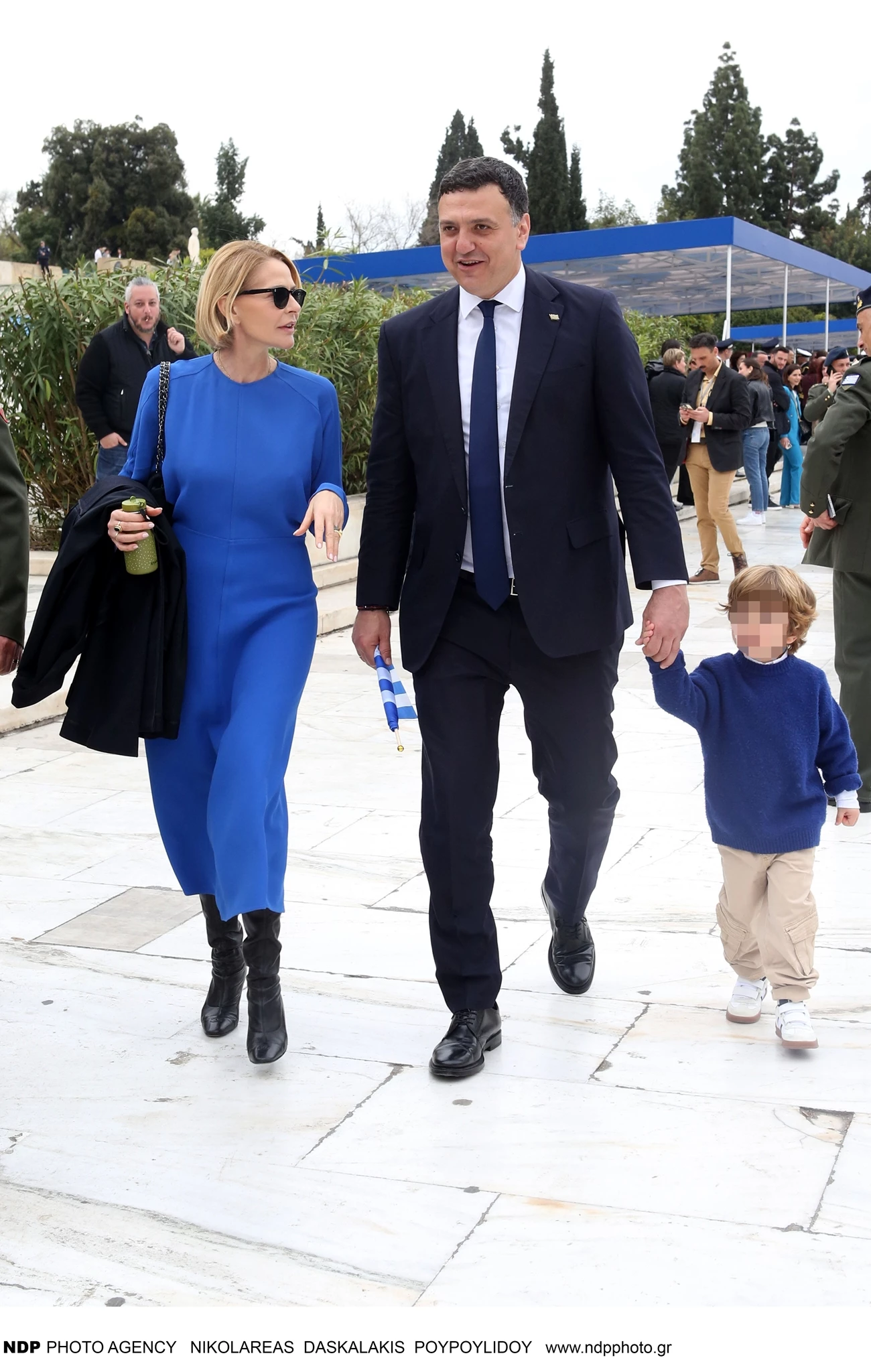 Η Τζένη Μπαλατσινού με μπλε φόρεμα στο πλευρό του Βασίλη Κικίλια στην παρέλαση της 25ης Μαρτίου