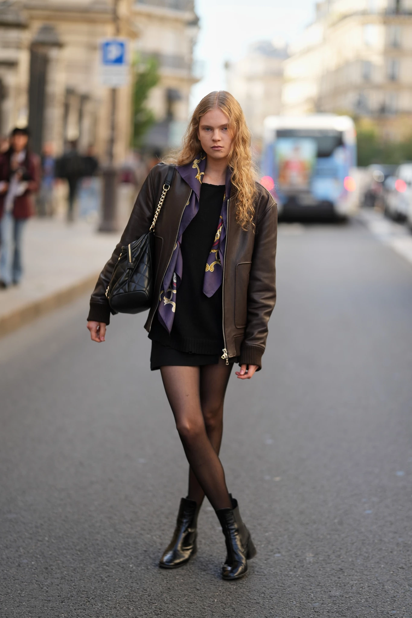 Γυναίκα με μαύρα μποτάκια και μαύρο δερμάτινο μίνι φόρεμα/φούστα με χοντρό καλσόν.