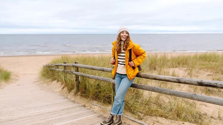 Stylish woman going coastline contemplating life on cold weather.