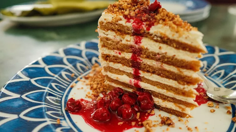 Honey cake with cherries on decorative plate with blue pattern, Tasty dessert