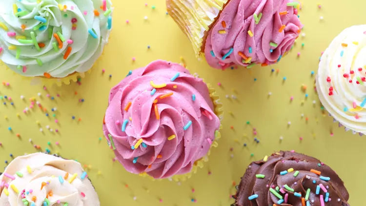 Image of colorful yellow cupcakes, buttercream frosting, rainbow sprinkles, overhead view, muffins, cakes, sweet treat photography