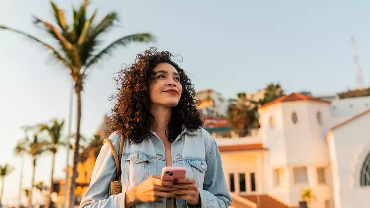 Young woman looking way holding mobile phone outdoor