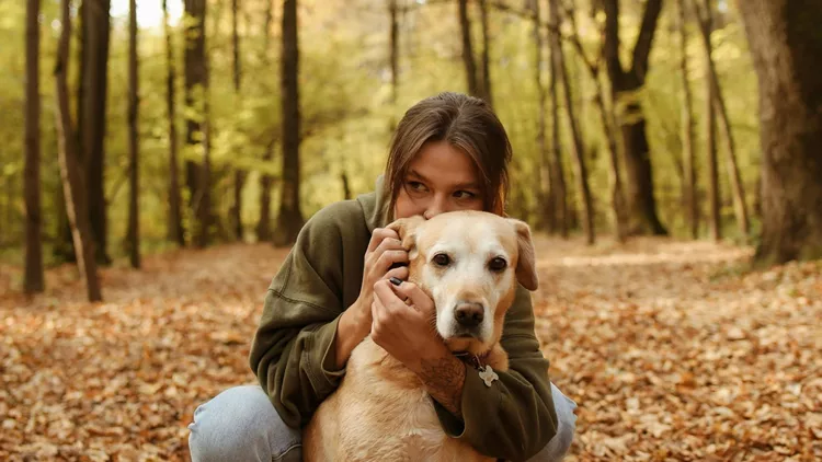 A Woman Hugging her Labrador Retriever Dog From the Back