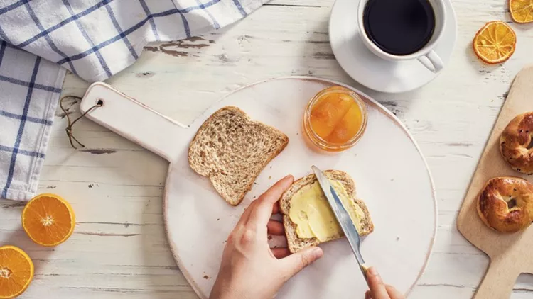 Woman hand spreading butter on sliced bread