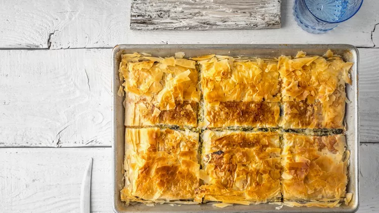 Greek pie spanakopita in metal pan  with tableware top view