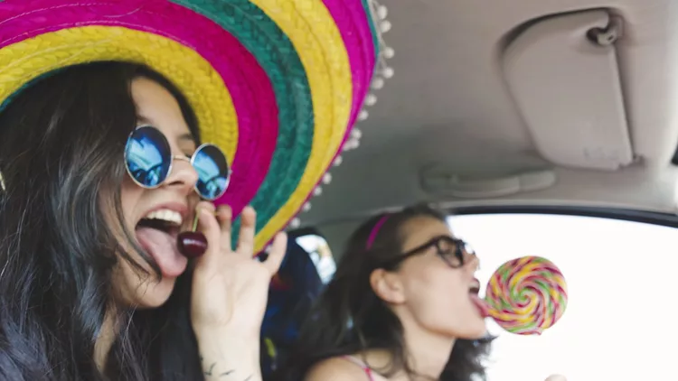 Two funny cheerful hipster women traveling in car