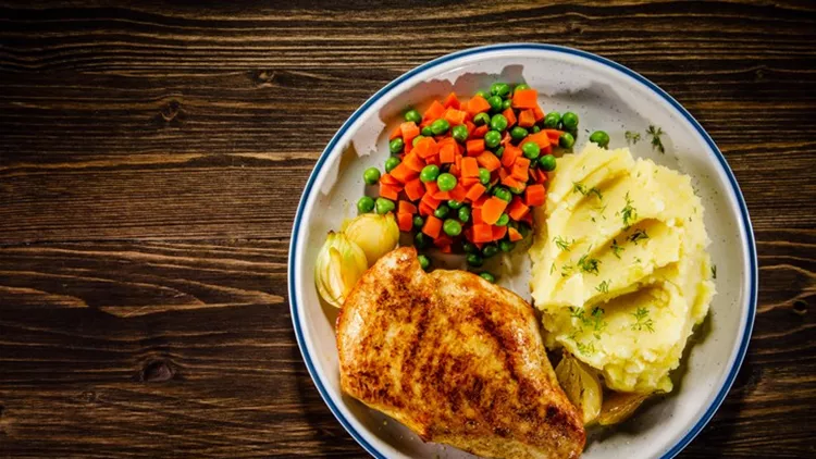 Barbecued chicken breast and vegetables on wooden background