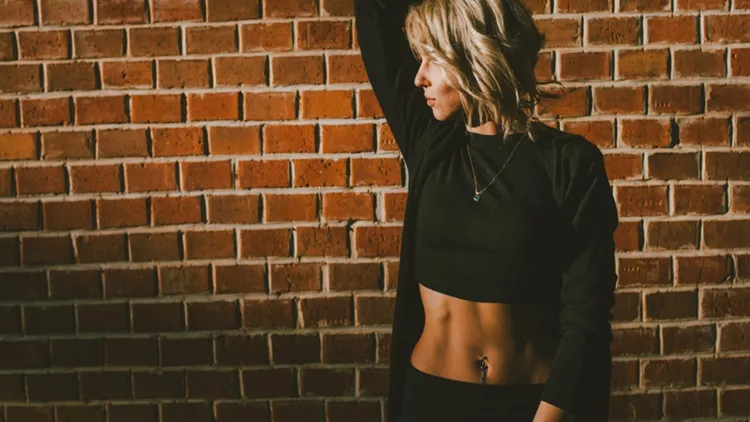 pretty-blond-woman-in-a-crop-top-standing-against-the-brick-wall-picture-id991939898 (1)