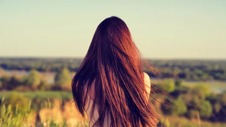 Young girl sits with his back to the camera and looks at nature