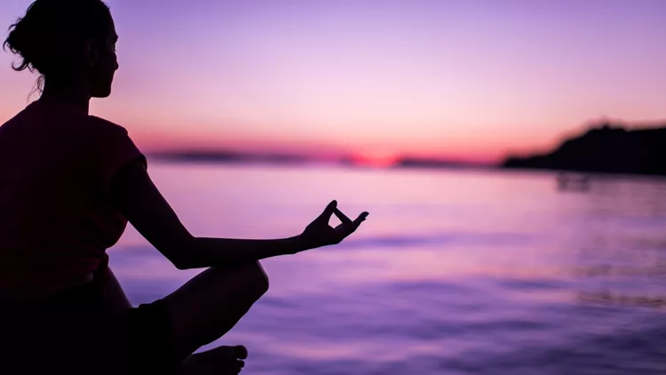 Young Woman Meditating By Peaceful Sea