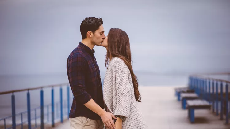 Young couple standing on pier and kissing.