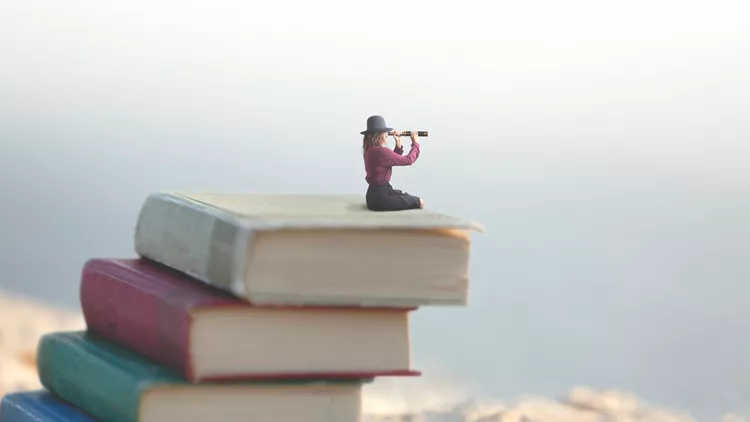 miniature woman looks at the infinity with the spyglass on a scale of books
