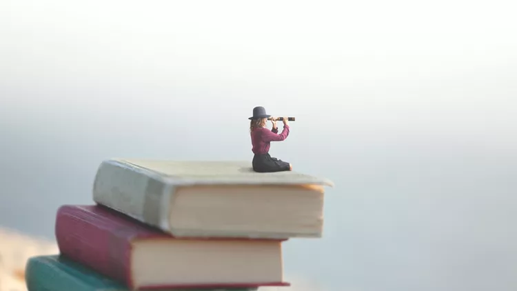 miniature woman looks at the infinity with the spyglass on a scale of books