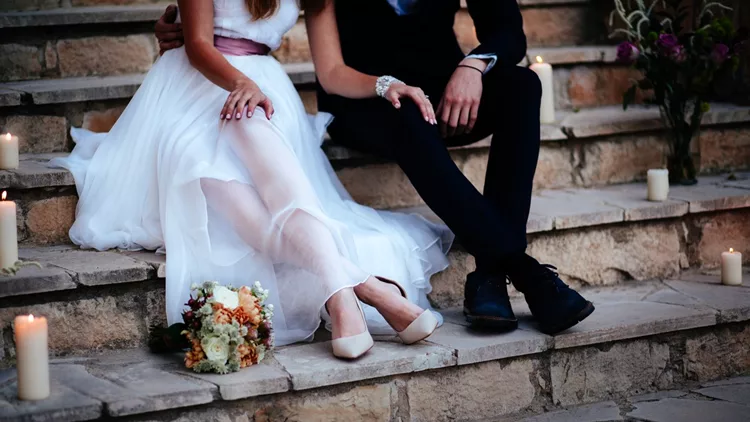 Young bride and groom relaxing together on stone steps