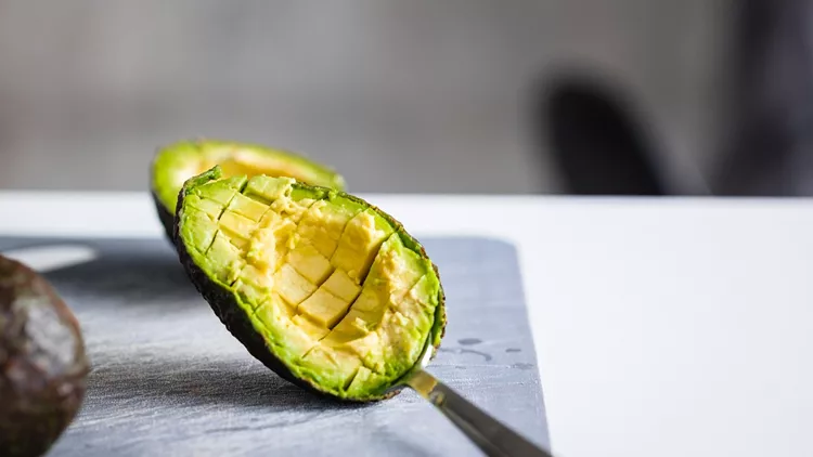 Ripe avocado cut on gray cutting board