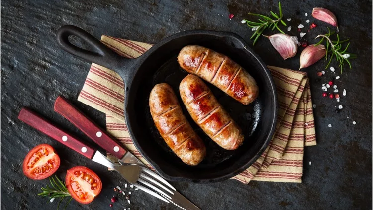 grilled-sausages-or-bangers-in-a-vintage-skillet-picture-id945574158