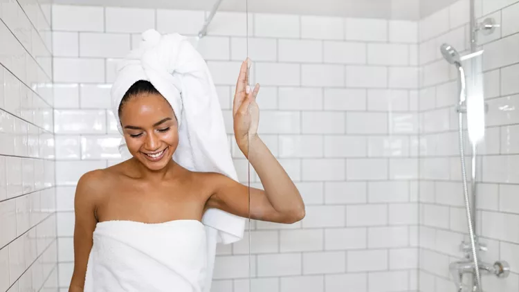 Young woman in white towels wrapped around head and body after shower