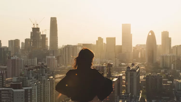 Rear view of Woman looking at city in Sunlight