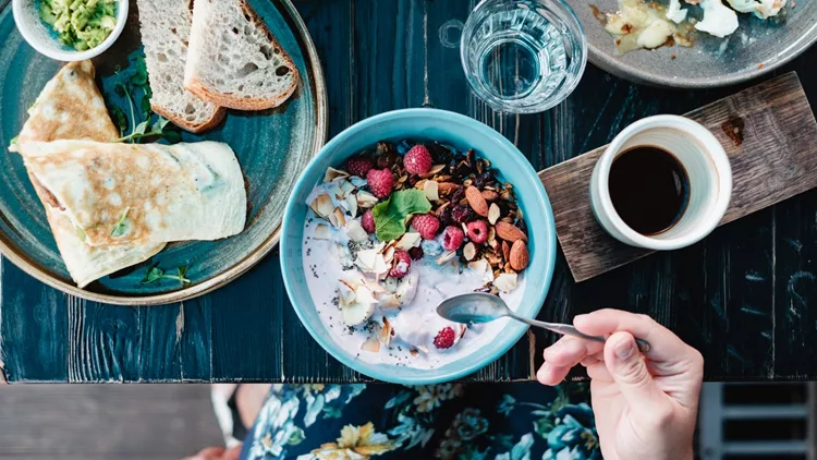 Woman eating natural yoghurt with granola and fresh berries