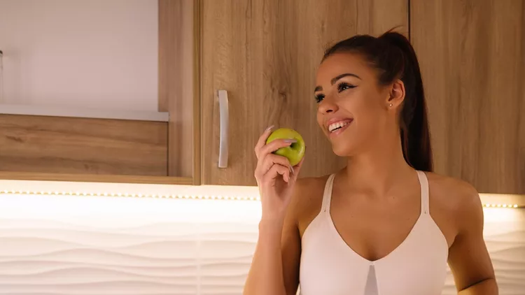 Beautiful young woman eating fruit for breakfast.