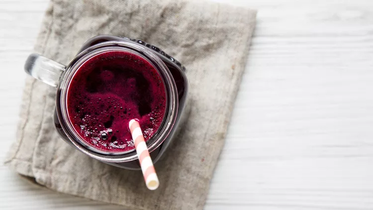 Glass jar of beetroot smoothie, top view. White wooden background. From above, overhead, flat lay. Copy space.