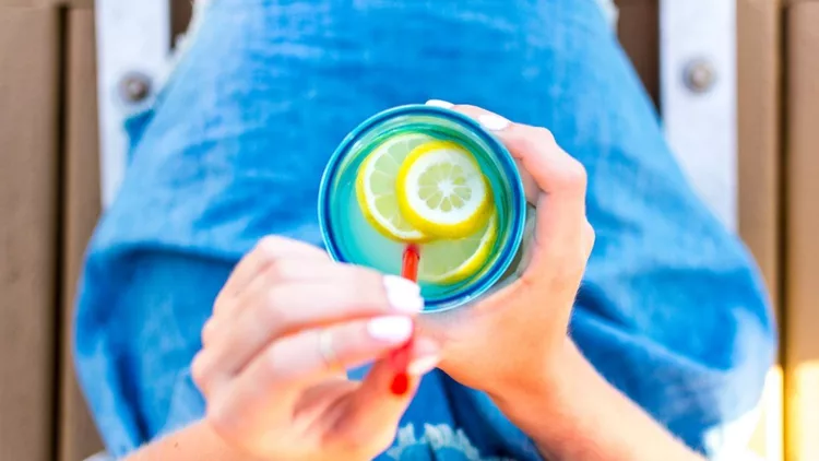 girl-woman-holding-a-mason-jar-with-lemons-lemonade-with-a-red-straw-picture-id864451458