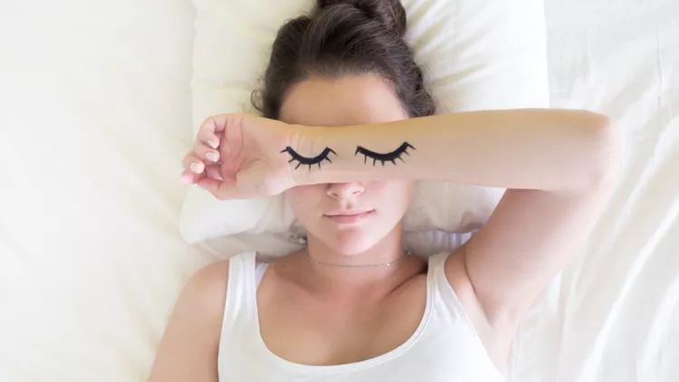 Painted sleeping eyes and brunette young woman in the bed at morning time