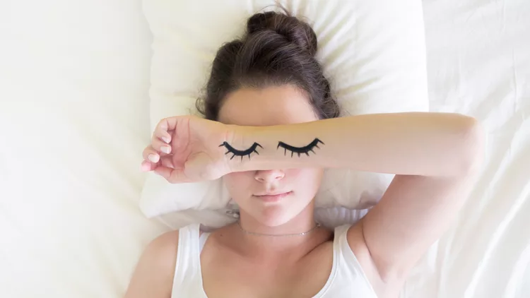 Painted sleeping eyes and brunette young woman in the bed at morning time
