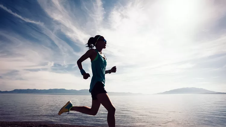 Young fitness sporty woman running on rocky seaside