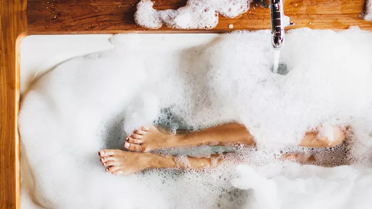 Woman legs in bath foam. Top view. Enjoying and relaxation in spa hotel
