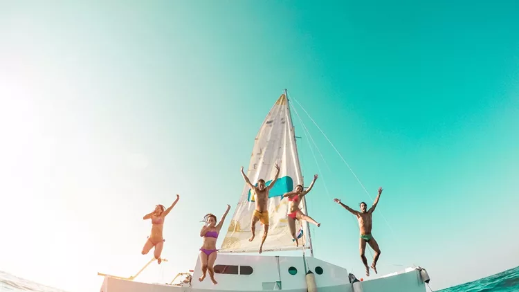 Happy crazy friends diving from sailing boat into the sea - Young people jumping inside ocean in summer vacation - Main focus on center guys - Travel and fun concept - Fisheye lens distortion