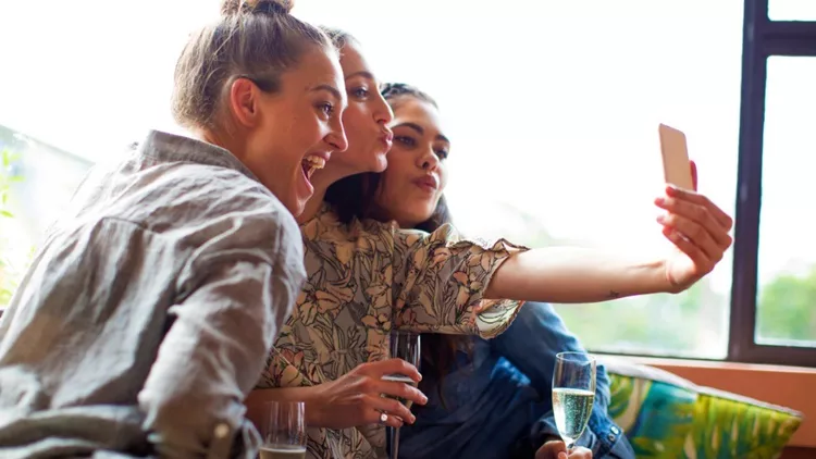 three-girlfriends-having-champagne-taking-selfie-picture-id519576978
