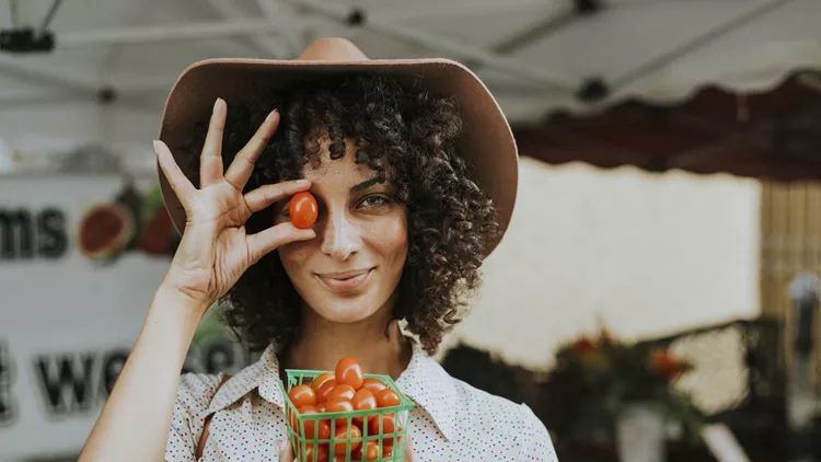 Beautiful woman buying tomatoes at a farmers market