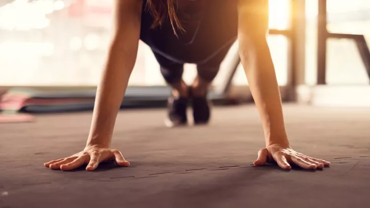 Close up woman hand doing push ups exercise in a gym in morning, sunlight effect.