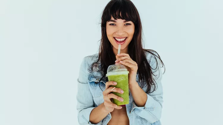 Beautiful woman drinking fresh green smoothie