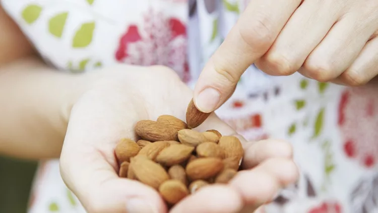 Woman Eating Handful Of Almonds