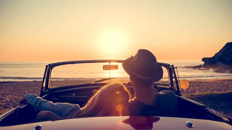 Couple watching the sunset in a convertible car.