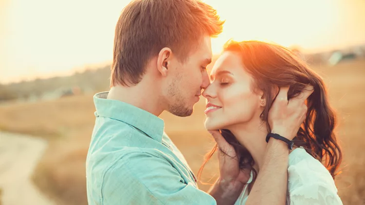 Young couple in love outdoor.in summer in field. Couple hugging. Young beautiful couple in love staying and kissing on the field on sunset. Soft sunny colors.
