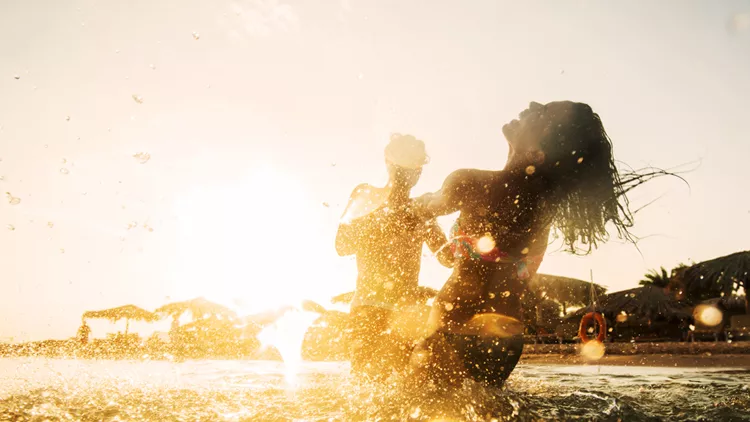 Playful couple in the sea at sunset.