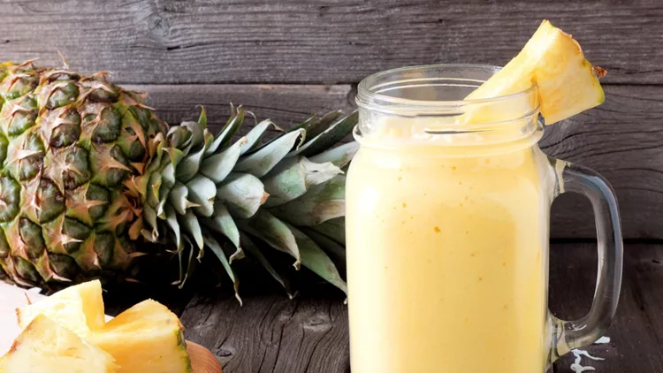Pineapple smoothie in a mason jar, scene against wood