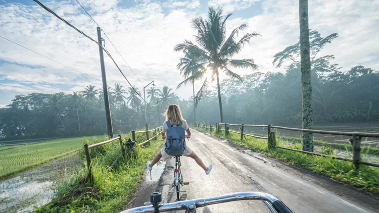 Personal perspective- couple cycling near rice fields at sunrise, Indonesia