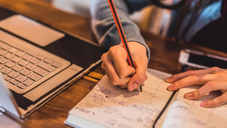 Close-up of young woman taking notes.