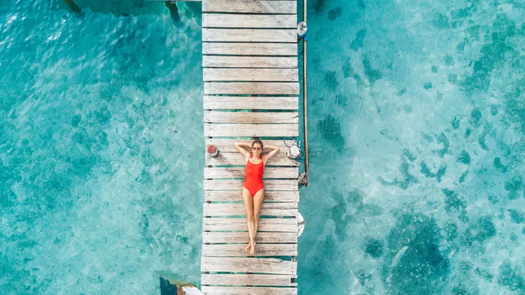 Aerial shot of womann relaxing in a water bungalow