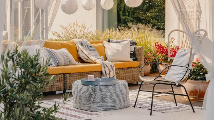 Real photo of an armchair, pouf as a table and wicker couch on a terrace