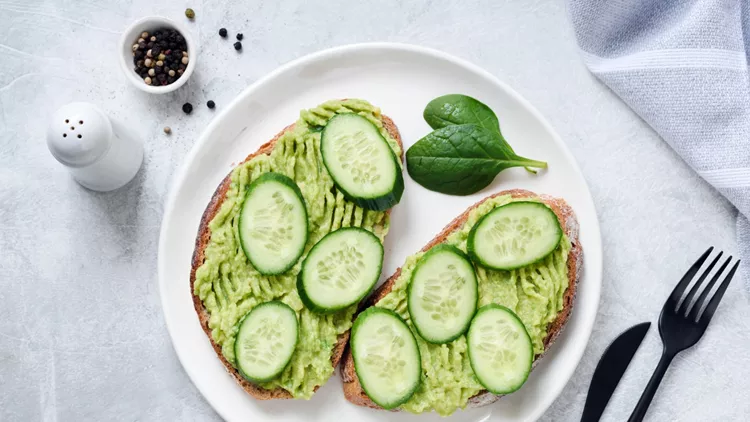 Toasts with avocado and cucumber on white plate