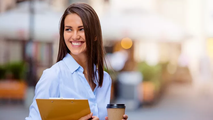 Beautiful young business woman smiling and holding documents and