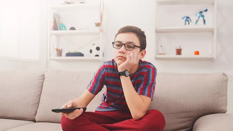 Bored teenage boy watching tv at home