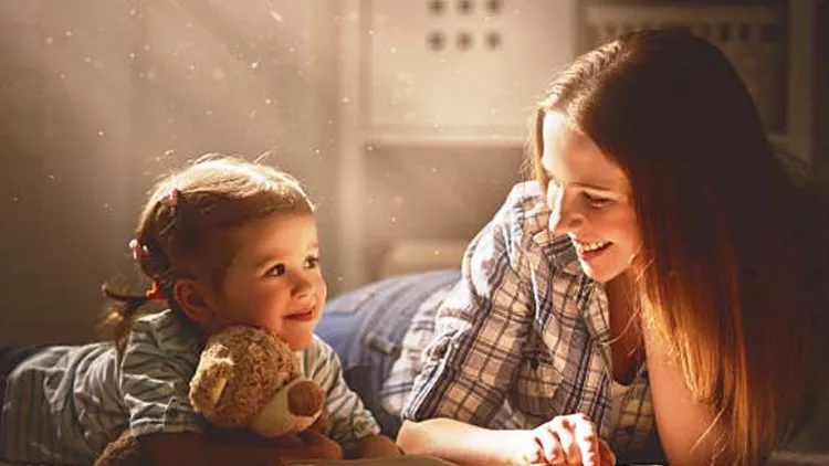 happy family mother and daughter read a book in evening
